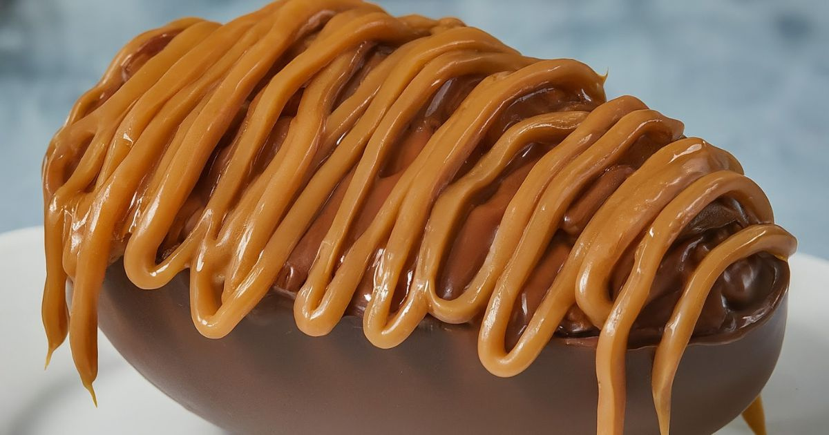 Ovo de chocolate recheado com paletas e coberto com calda de caramelo salgado