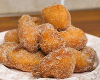 Porção de bolinho de chuva com canela e açúcar no prato