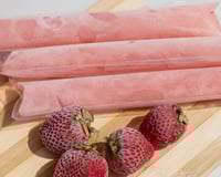 Geladinho de morango caseiro no sacolé com a fruta do lado