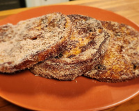 Três fatias de rabanada de panetone na airfryer no prato laranja