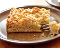 Fatia de cuca em um prato com farofa doce por cima