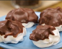 Porção de suspiro caseiro coberto com chocolate no prato azul