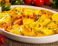 Moqueca de bacalhau em travessa com pimentões fatiados