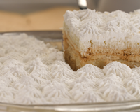 Pavê de bolacha de maizena coberto com chantilly sendo cortado