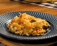 Arroz com bacalhau, legumes e temperos no prato azul