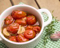Tomate confit servido em pote com azeite, alho e ervas
