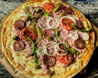Pizza portuguesa caseira com cebola, tomate e outros