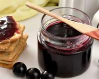 Geleia de jabuticaba no pote aberto com torrada e a fruta do lado