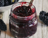 Geleia de amora caseira no pote de vidro com a fruta do lado