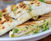 Pão pita com iogurte, queijo cottage e acelga, servido numa frigideira: receita fácil perfeita para um lanche delicioso