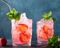 Dois drinks com gin, morango e hortelã em copos com canudo