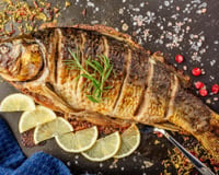 Peixe assado com recheio em travessa com rodelas de limão