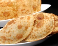 Pastel em forma de meia lua e em quadrado em duas tigelas