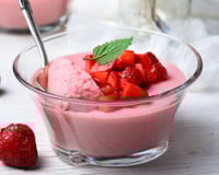 Gelatina cremosa servida em copo com morangos picados