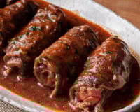 Porção de bife à rolê em um prato caprichado com molho