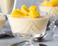 Mousse de manga cremosa servida em taça com pedaços da fruta
