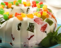 Gelatina colorida com creme de leite condensado e frutas em cima