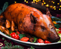 Leitoa à pururuca servida em prato com batatas e tomates