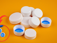 Por que tem um disco de plástico sob a tampa da garrafa de refrigerante?