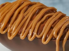 Ovo de chocolate recheado com paletas e coberto com calda de caramelo salgado