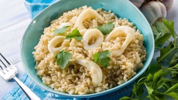 Risoto de lula em anéis em prato azul finalizado com folhas de coentro (Créditos: Shutterstock)