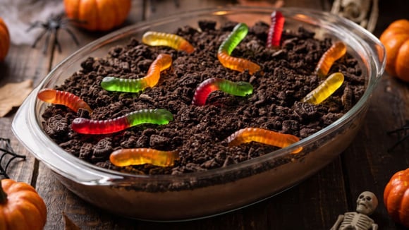 Pudim de terra para o Halloween na travessa com minhocas de gelatina (Créditos: Gerado por IA)