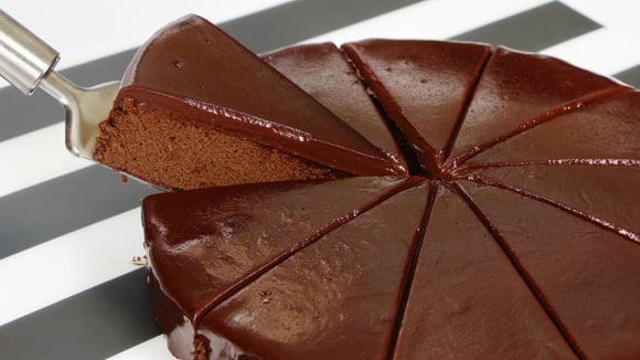 Bolo de chocolate com flocão e calda de chocolate cortado em fatias triangulares (Créditos: Canva)