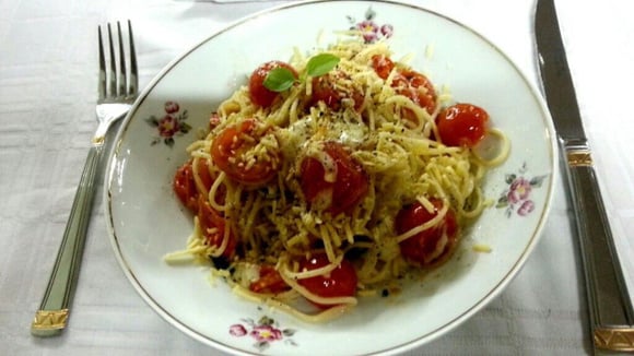 Espaguete com tomates-cereja, mussarela de búfala e manjericão em prato com garfo e faca (Créditos: TudoGostoso/Cassidi Locatelli)