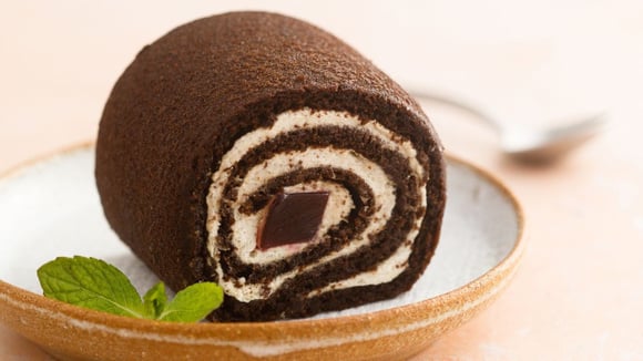  
Rocambole gelado de leite em pó e chocolate com recheio cremoso de coco em prato (Créditos: Shutterstock)