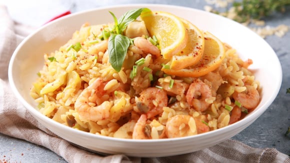 Risoto de camarão com meias-rodelas de limão e temperos diversos no prato branco (Créditos: Shutterstock)