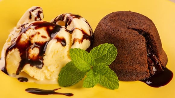 Petit gâteau partido ao meio com recheio escorrendo e servido com sorvete de creme com calda de chocolate (Créditos: TudoGostoso)