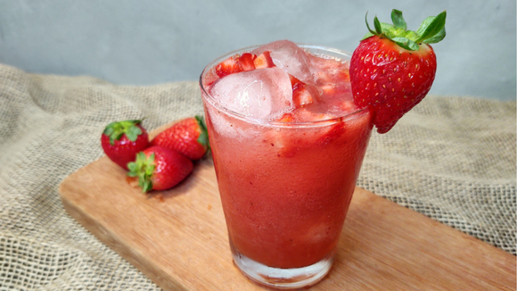 Suco de morango em copo com cubos de gelo e decorado com a fruta inteira (Créditos: Shutterstock)