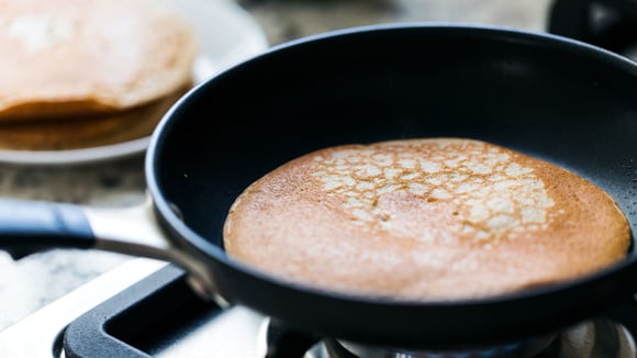 Enquanto a massa está cozinhando, a dica é colocar pequenos pedacinhos de manteiga na frigideira para deixar a panqueca dourada (Créditos: Shutterstock)
