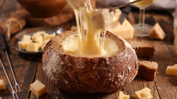 Fondue de queijo no pão italiano grande e redondo com pedacinhos de pães (Créditos: Shutterstock)