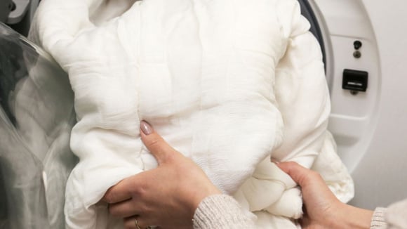 Antes de colocar o edredom na máquina, é essencial conferir a etiqueta da peça para verificar se pode ser lavada assim (Créditos: Shutterstock)