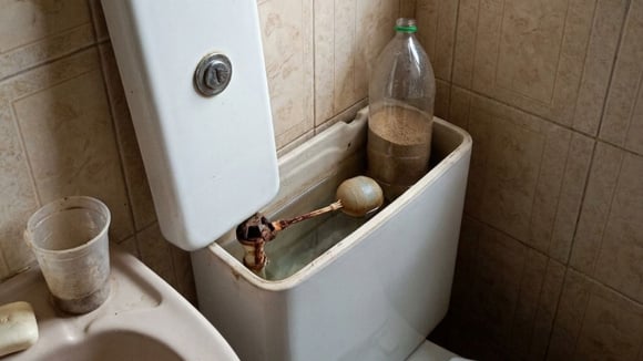 Garrafa PET com areia dentro de caixa acoplada de vaso sanitário (Créditos: Gerado por IA)
