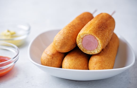 O cachorro-quente no palito é bom para comer sem largar a bebida (Créditos: Shutterstock)