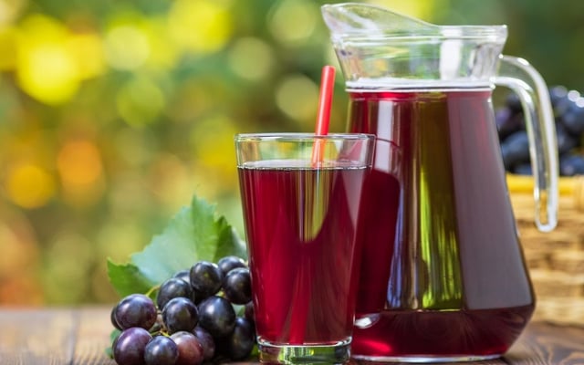 Suco de uva concentrado caseiro na jarra e no copo ao ar livre