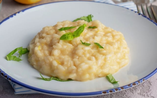 Risoto de queijo cremoso com ervas por cima no prato fundo