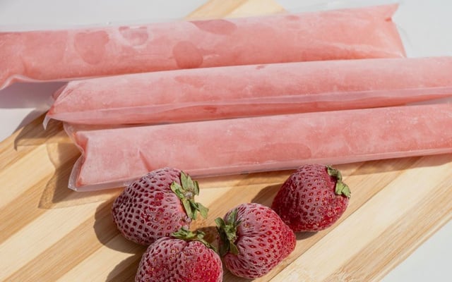 Geladinho de morango caseiro no sacolé com a fruta do lado