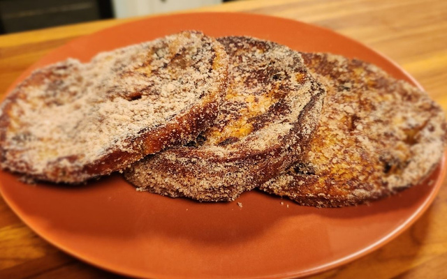 Três fatias de rabanada de panetone na airfryer no prato laranja