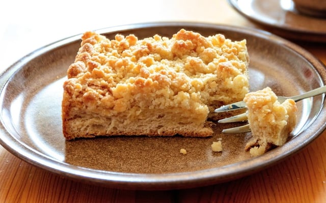 Fatia de cuca em um prato com farofa doce por cima