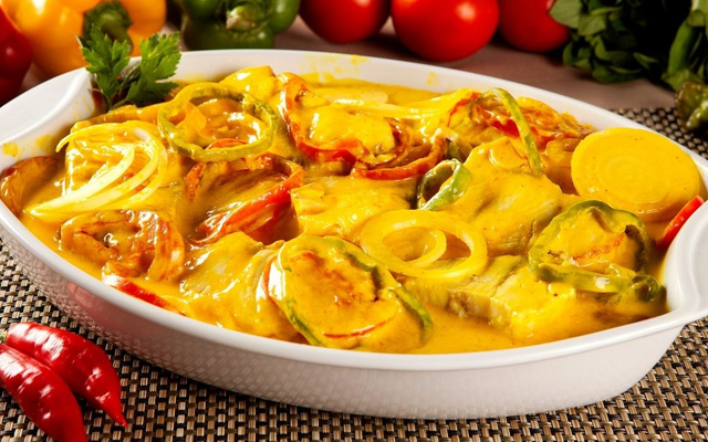 Moqueca de bacalhau em travessa com pimentões fatiados