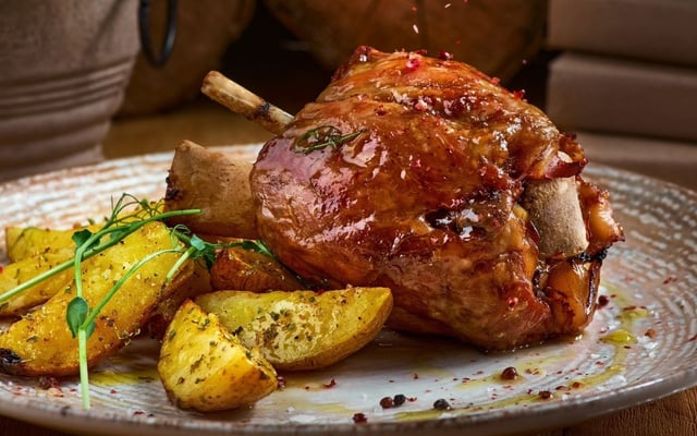 Pernil assado com batata rústica e temperos no prato completo