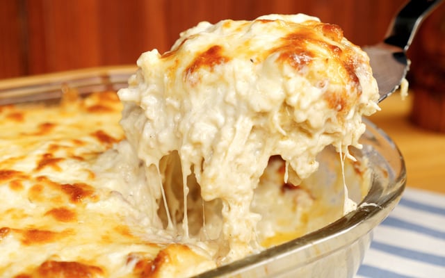 Lasanha de frango com queijo cremosa e gratinada sendo fatiada