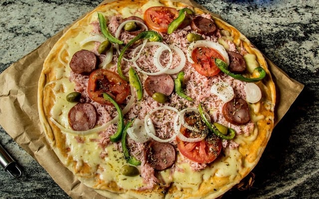 Pizza portuguesa caseira com cebola, tomate e outros