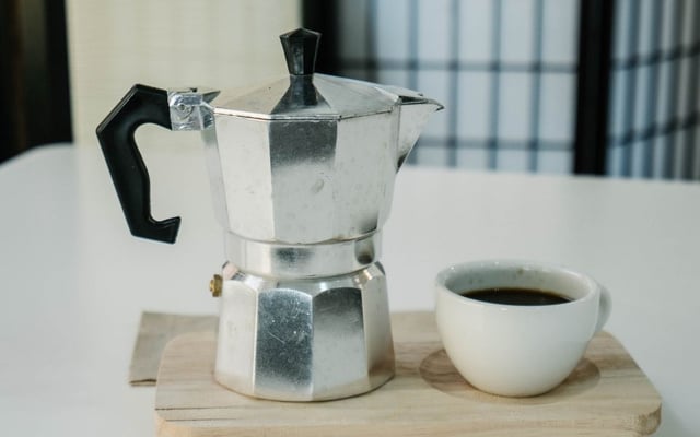 Café na cafeteira italiana fresco ao lado de uma xícara cheia