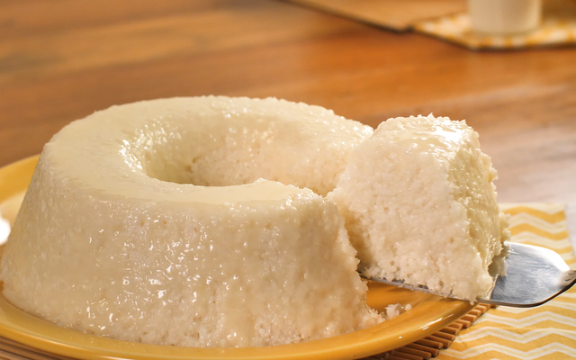 Bolo de tapioca cremoso redondo com fatia sendo cortada