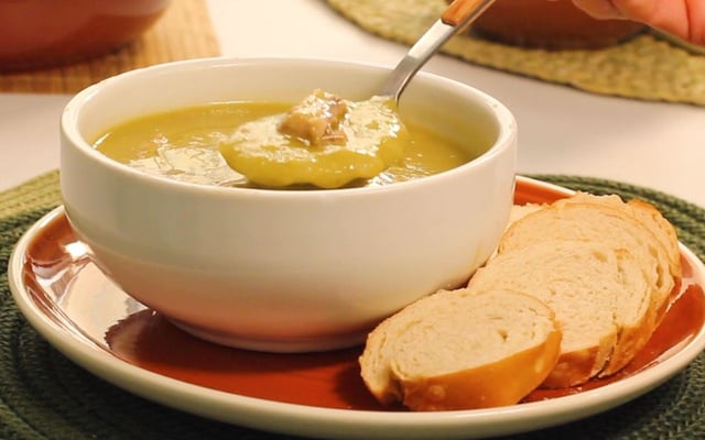 Sopa de ervilha na tigela acompanhada de rodelas de pão