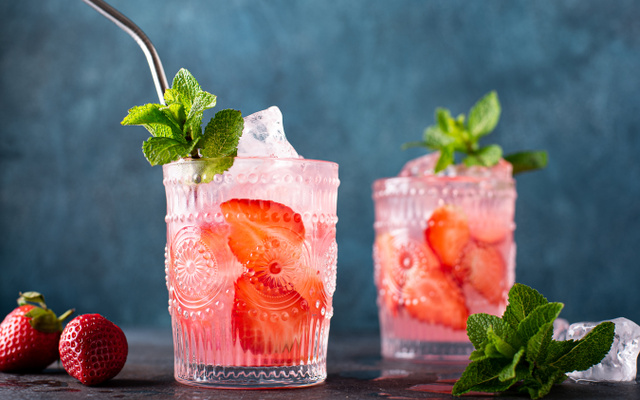 Dois drinks com gin, morango e hortelã em copos com canudo